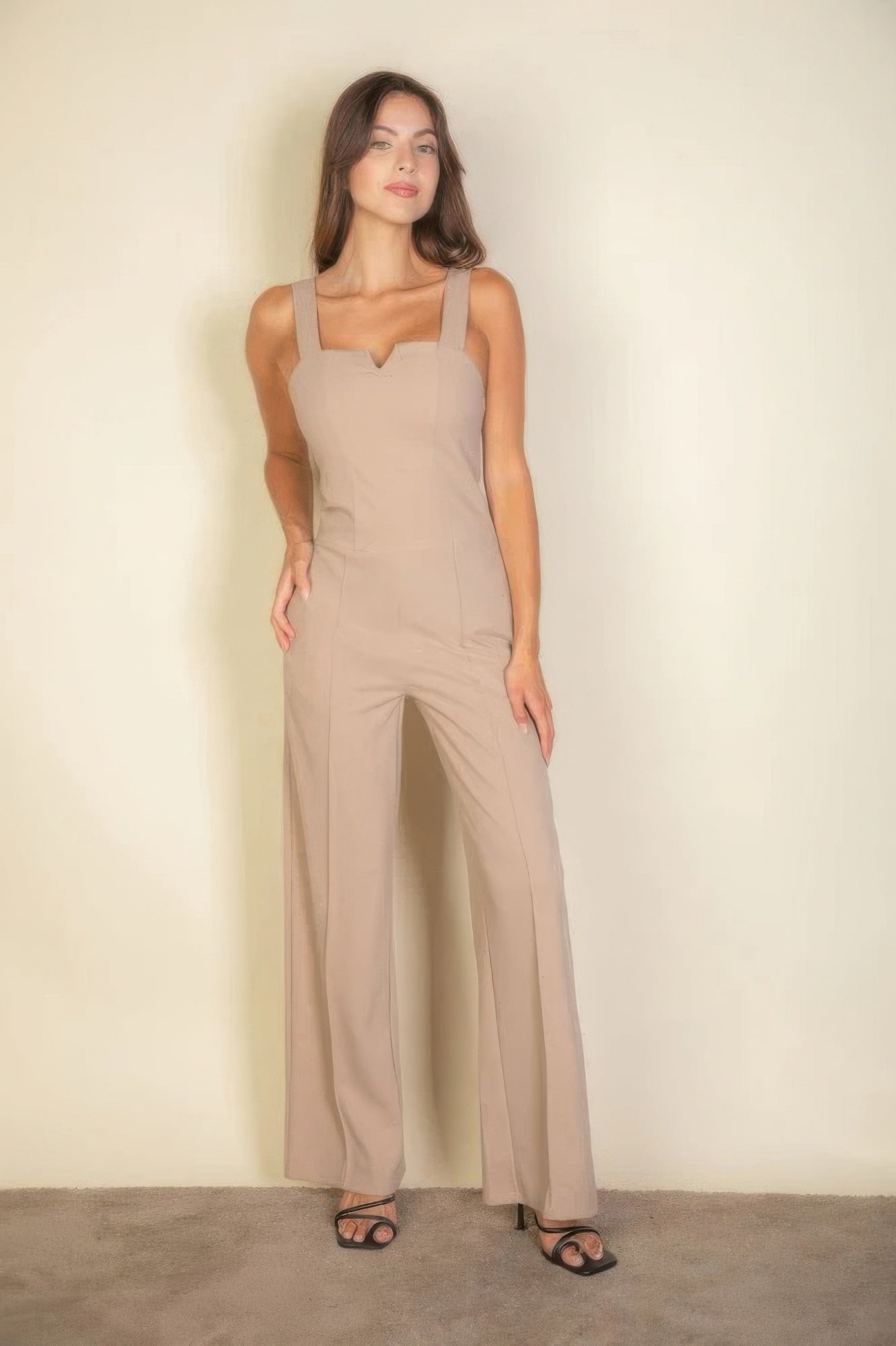 Woman wearing taupe notched neck cami jumpsuit with wide legs and sleeveless design